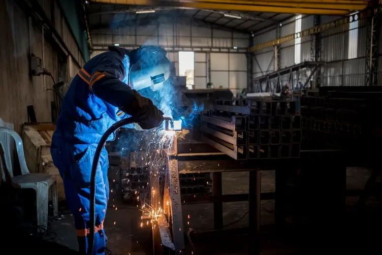 Welder or supervisor checking a job on a tablet in the workshop